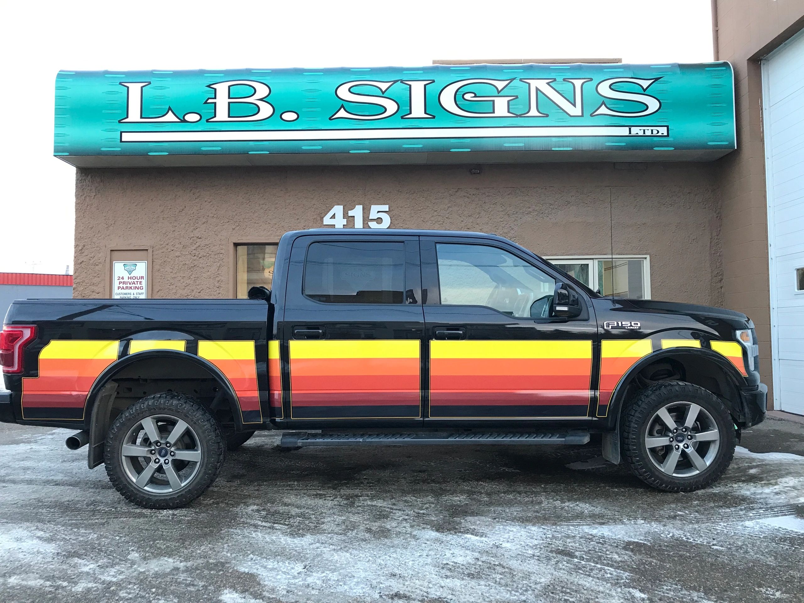 LB Signs storefront at 415 23rd Street West with a custom-striped black pickup parked outside